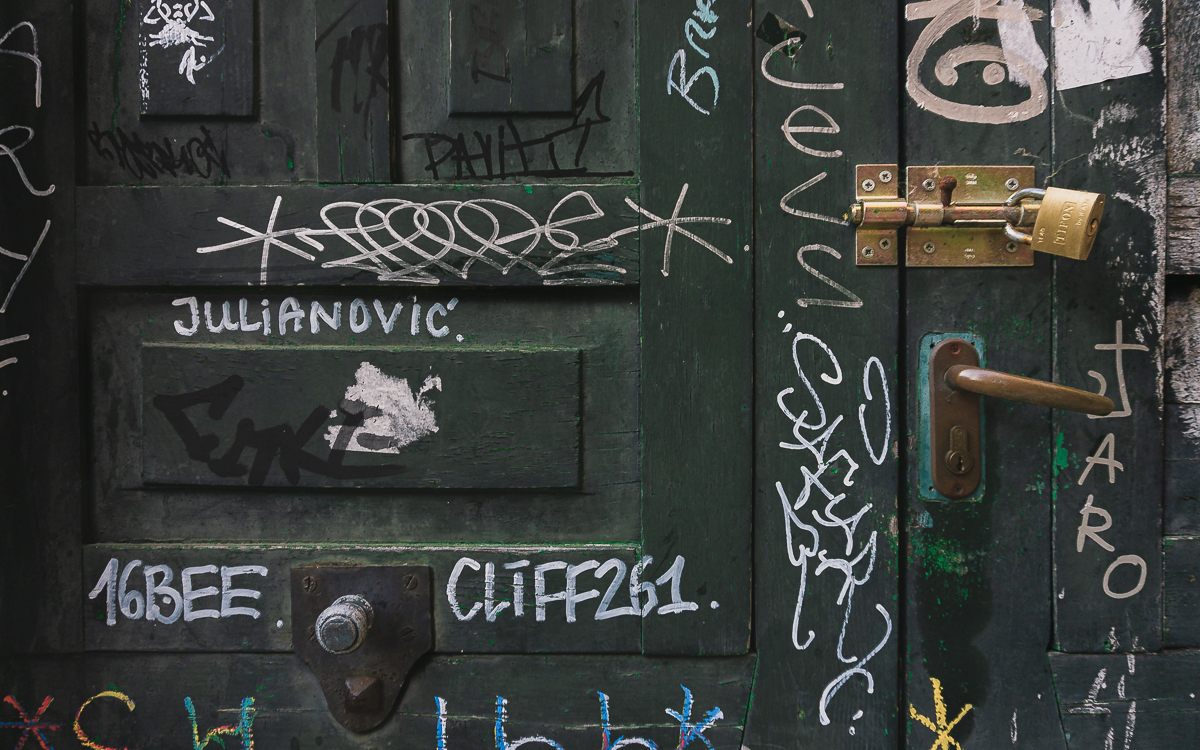 Primer plano de puerta antigua candada con pintadas.