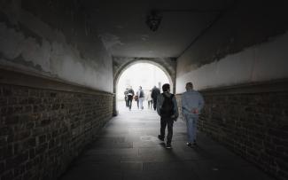 Personas atravesando un túnel transitable que desemboca en la Praza dos Bombeiros.