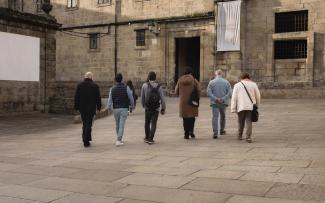 Vista de espalda de 6 personas caminando hacia la Hospedería de San Martín Pinario en Santiago