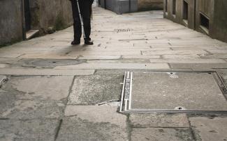 Enfoque de las piernas de una persona con bastón guía caminando en el casco antiguo de Santiago. 
