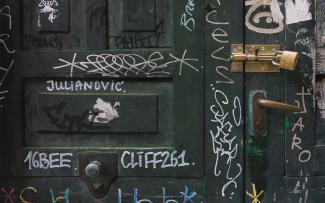 Primer plano de puerta antigua candada con pintadas.