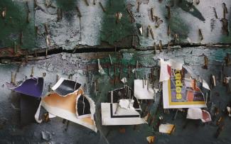 Composición artística de ventana de calle, repleta de grapas con requicios de carteles publicitarios