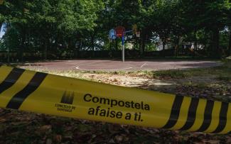 Cinta de aviso del ayuntamiento que dice "Compostela se amolda a ti" con fondo de pista de Bascket.