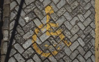 Suelo adoquinado con señal de "reservado para personas con movilidad reducida" muy deteriorada.